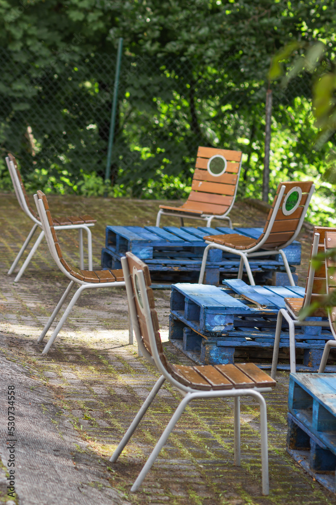 Summer cafe area with blue wooden tables and vintage chairs in the old marine style in quiet place of backyard. Summer cafe area with blue wooden tables and vintage chairs in the old marine style in quiet place of backyard.