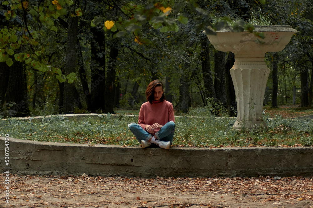 A woman in Casual clothes does yoga in an old park A woman in Casual clothes does yoga in an old park