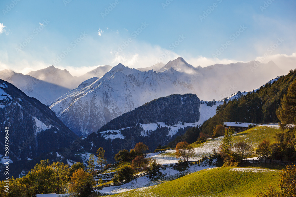 Valley in the alps at autumn with snow covered mountain peaks