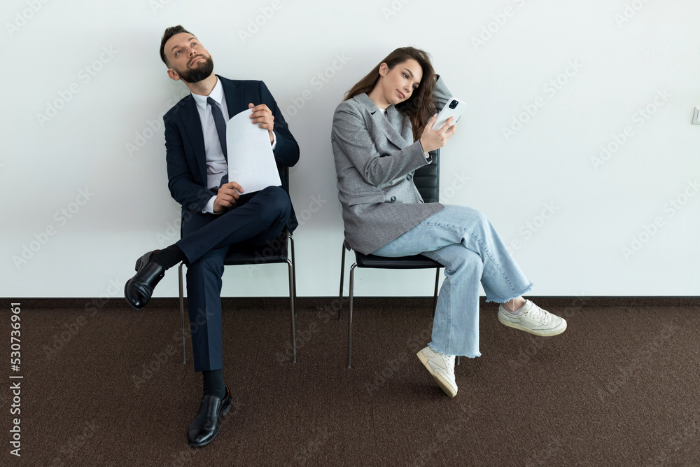 office employees sit on chairs man and woman waiting for an interview office employees sit on chairs man and woman waiting for an interview
