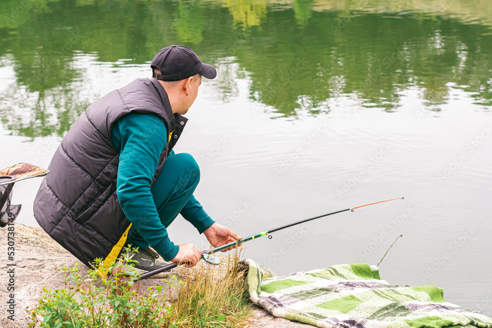 Man on a fishing rod in his hands catches fish on the river Man on a fishing rod in his hands catches fish on the river