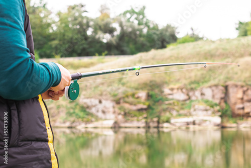 Man on a fishing rod in his hands catches fish on the river © Владислав Легір