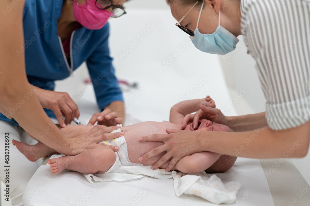 Baby beeing vaccinated by pediatrician in presence of his mother. Preventive vaccination against Diphtheria, whooping cough, tetanus, hepatitis, haemophilus influenzae, pneumococcus, poliomyelitis