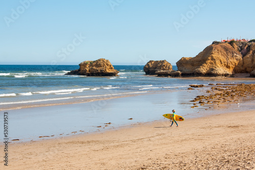 Torquay, Victoria / Australia - January 1 2015: young kid surfer at the beach caring a surfboard and walking self-assured to the sea. Great Ocean Road summer holiday. Children and surfing concept.  photo