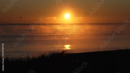 Steamy sunrise over Pukehina Beach, New Zealand photo