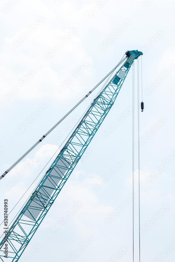 Large green crane boom with hooks with sky background Large green crane boom with hooks with sky background