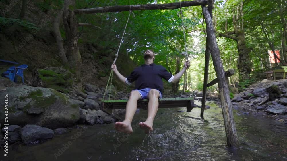 Young man swinging on a swing above the water. Slow Motion.
Water touches the feet of the young man swinging on the swing.
Young man swinging on a swing above the water. Slow Motion.
Water touches the feet of the young man swinging on the swing.