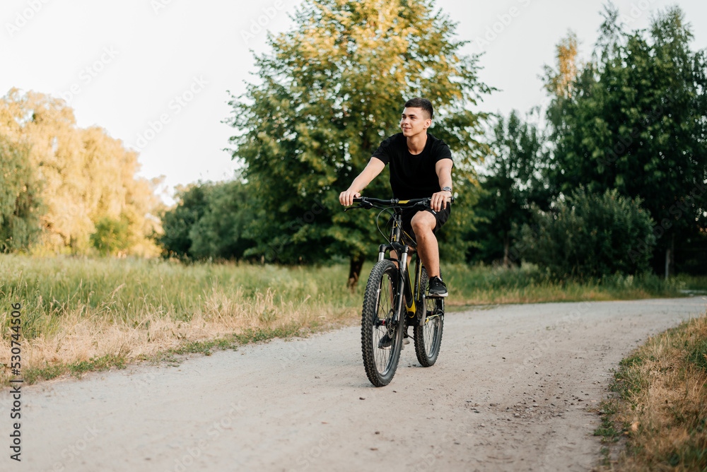 Fototapeta premium A man rides a bicycle along a path in the park
