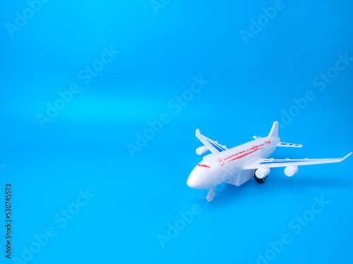White toy airplane on a blue background with copy space.