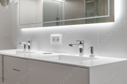 Fototapeta Naklejka Na Ścianę i Meble -  Brand new water taps and double sink in luxury bathroom. Modern mirror with lightning.