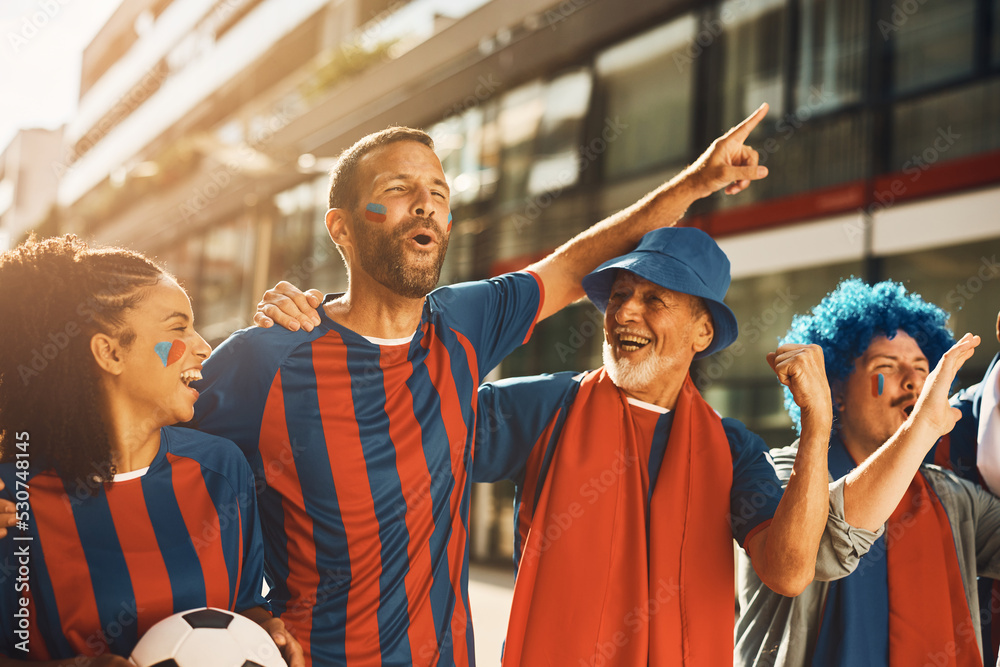 Happy sports fan and his friends have fun while going on soccer match and shouting  on the street.