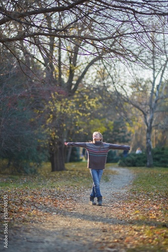 A girl in a knitted sweater in an autumn park. September or October, yellow leaves on trees.