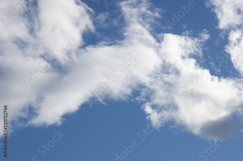 Snow-white clouds against a bright blue sky. Bright background with sunlight in the middle of the day