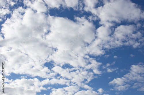 Snow-white clouds against a bright blue sky. Bright background with sunlight in the middle of the day