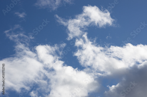 Snow-white clouds against a bright blue sky. Bright background with sunlight in the middle of the day