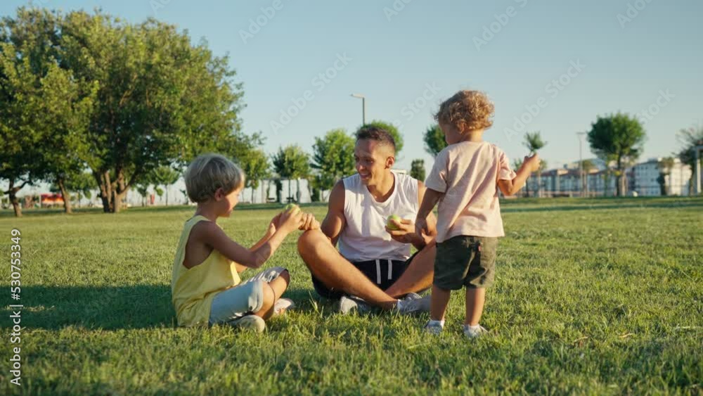 Happy father juggling with green apples in the park with his kids. High quality 4k footage Happy father juggling with green apples in the park with his kids. High quality 4k footage
