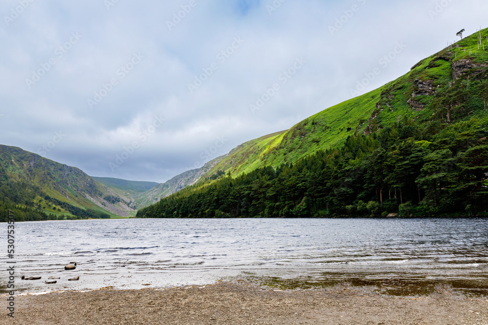 Idyllic view in Glendalough Valley, County Wicklow, Ireland. Mountains, lake and tourists walking paths Idyllic view in Glendalough Valley, County Wicklow, Ireland. Mountains, lake and tourists walking paths