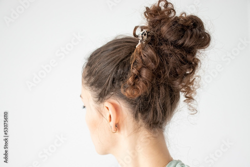 A woman's curly hair is gathered in a bunch.