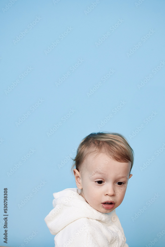 a little boy of 2 years sits in a white jacket on a blue background and thinks laughs happy sad sadness cheerful advertisement for children a little boy of 2 years sits in a white jacket on a blue background and thinks laughs happy sad sadness cheerful advertisement for children