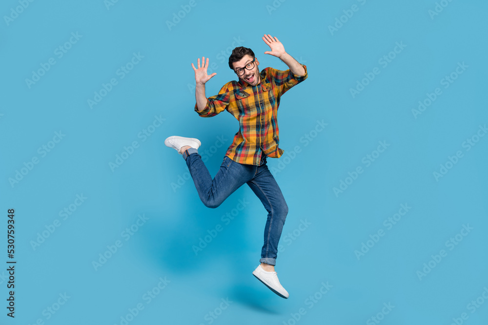 Full body portrait of satisfied sportive person jumping have good mood isolated on blue color background