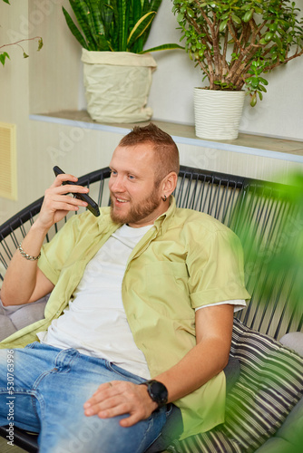 Happy smiling man holding mobile phone speaking talking with friends or family using loudspeake photo