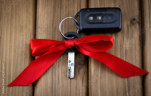 Close-up view of car keys with red bow as present on  wooden background