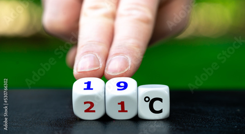Hand turns dice and changes the expression "21 degrees Celsius" to "19 degrees Celsius". Symbol for lowering the temperature in offices to reduce the energy consumption.