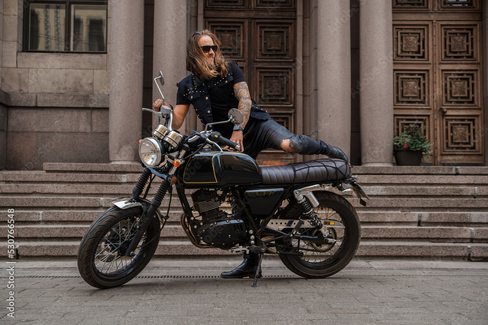 Shot of brutal motorcyclist with beard and long hairs driving motorbike.