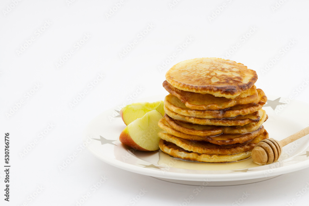 Stack of pancakes with apple slices and honey on the plate isolated on white background Stack of pancakes with apple slices and honey on the plate isolated on white background