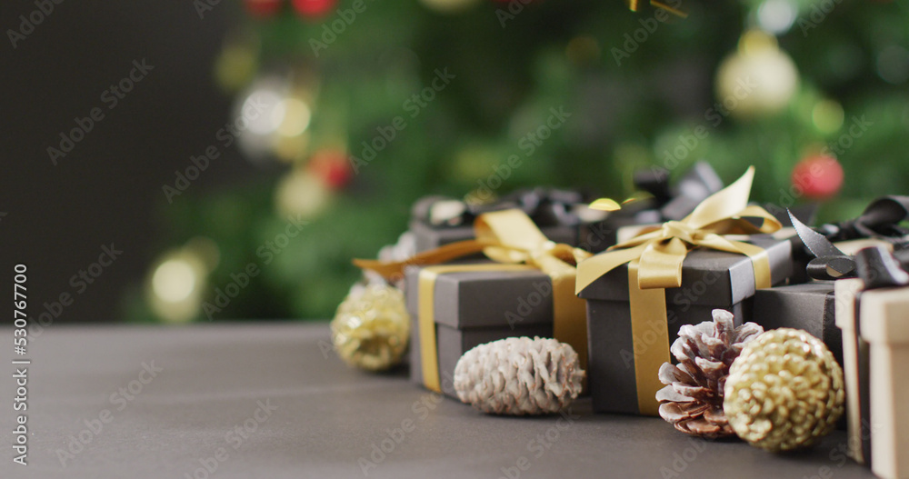 Image of christmas gifts with pine cones and copy space on black background