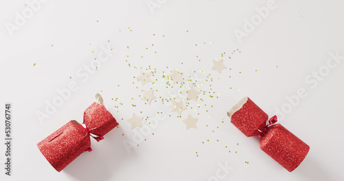 Image of red christmas cracker, stars and decoration with copy space on white background