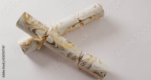 Image of two white and gold christmas crackers and copy space on white background