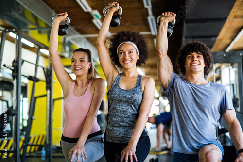 Group of fit people lifting dumbbells during an exercise class at the gym Fototapet