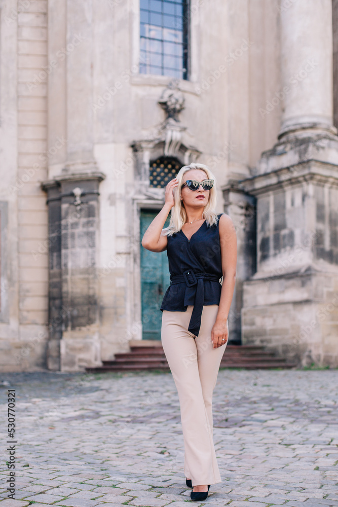 A young, slender blonde in beige pants and a black blouse walks the old streets of Lviv. Ukraine. A young, slender blonde in beige pants and a black blouse walks the old streets of Lviv. Ukraine.
