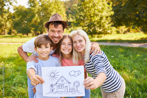 Glückliche Familie mit Zeichnung vom Traumhaus photo