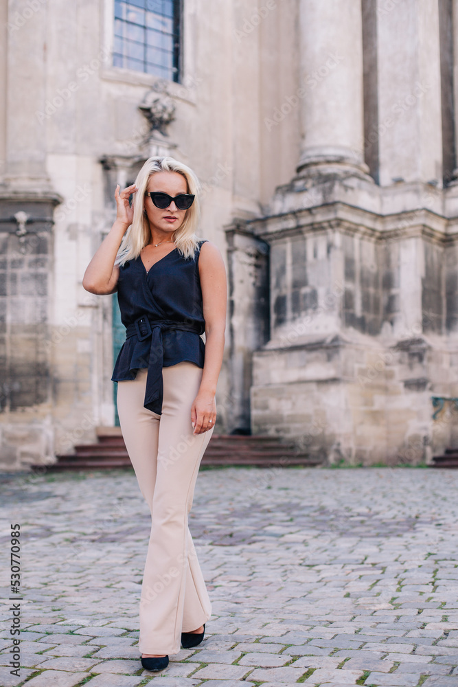 A young, slender blonde in beige pants and a black blouse walks the old streets of Lviv. Ukraine. A young, slender blonde in beige pants and a black blouse walks the old streets of Lviv. Ukraine.