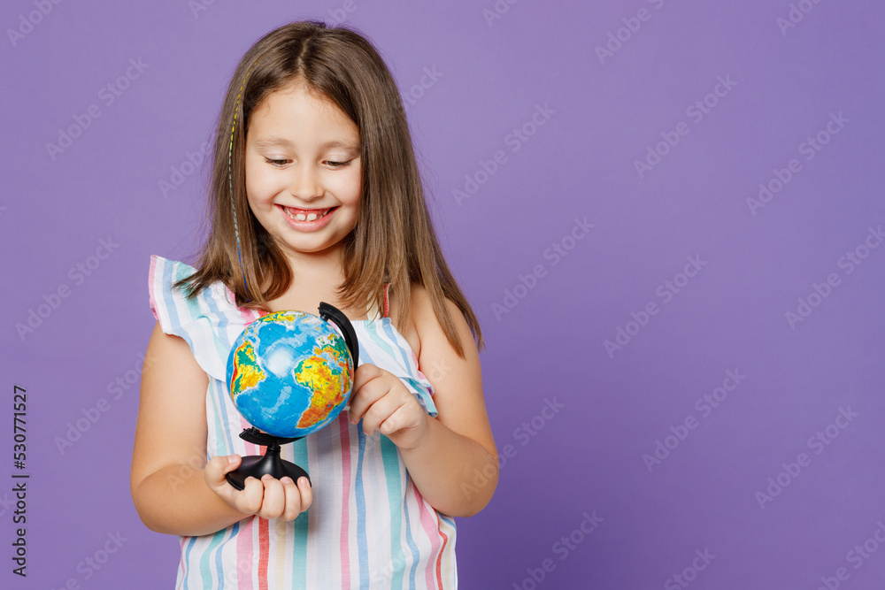 Little kid child girl 5-6 years old in striped dress hold in hands spin Earth world globe choosing country isolated on plain pastel light purple background Mother's Day love family lifestyle concept Little kid child girl 5-6 years old in striped dress hold in hands spin Earth world globe choosing country isolated on plain pastel light purple background Mother's Day love family lifestyle concept