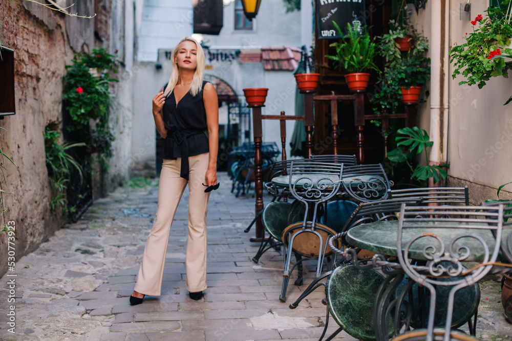 A young, slender blonde in beige pants and a black blouse walks the old streets of Lviv. Ukraine. A young, slender blonde in beige pants and a black blouse walks the old streets of Lviv. Ukraine.