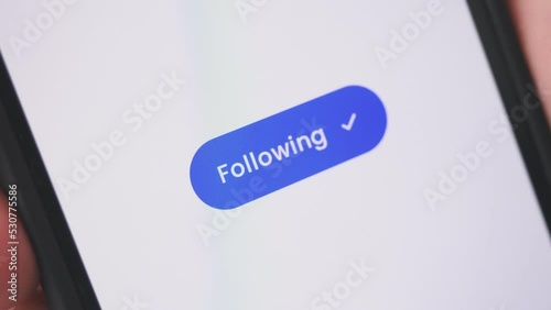 Young lady pressing follow button on smartphone. Social media concept.