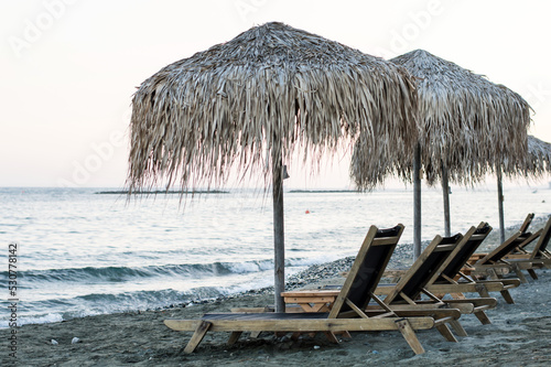 Beach chairs with straw umbrellas on a beautiful tropical beach