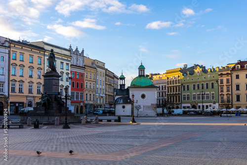 Main Market Square with Church of St. Wojciech, Adam Mickiewicz Monument and colorful houses. Early morning. Kraków, Poland.