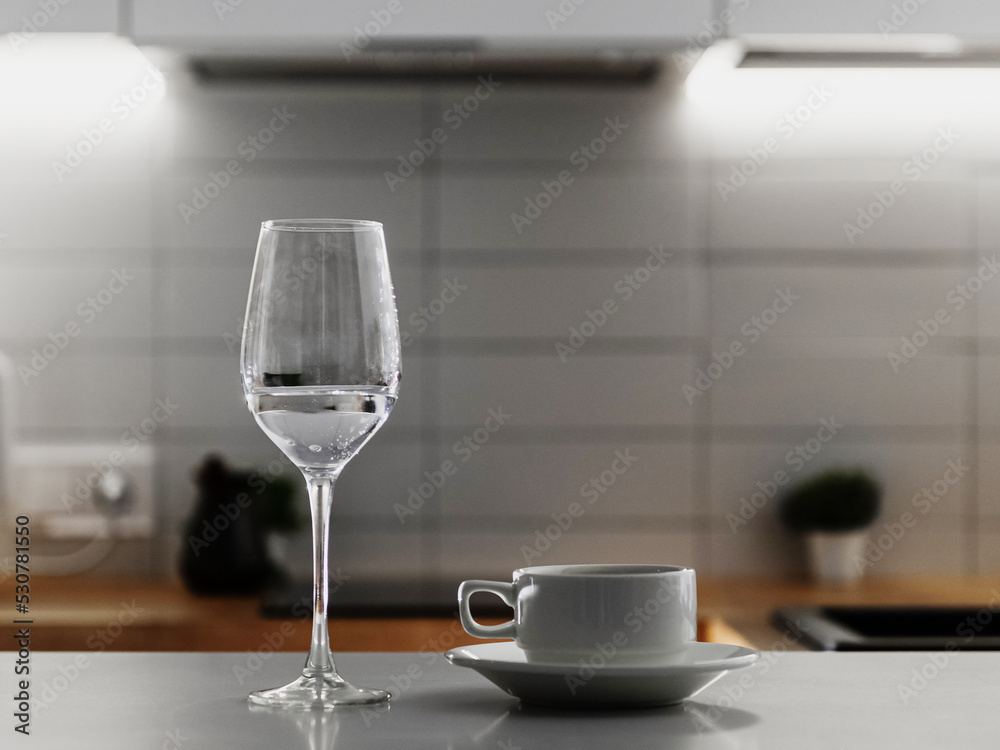 An empty coffee glass and an empty glass of wine are on the kitchen table. An empty coffee glass and an empty glass of wine are on the kitchen table.