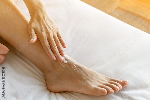 A woman takes care of her legs and puts a moisturizer on it. The concept of taking care of the skin on the legs