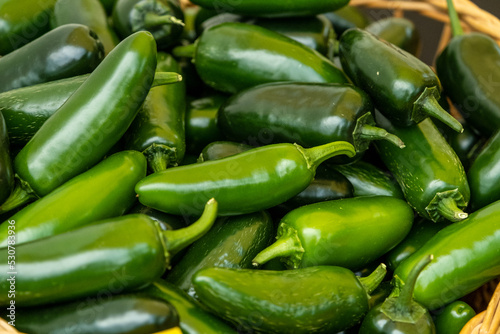 close up view of a pile of green chili pepper in harvest season placed in a market or bazaar for sale.
