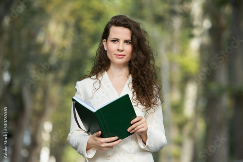Portrait of a business woman with a notebook in her hand. Smartly dressed girl outside. Successful white european woman