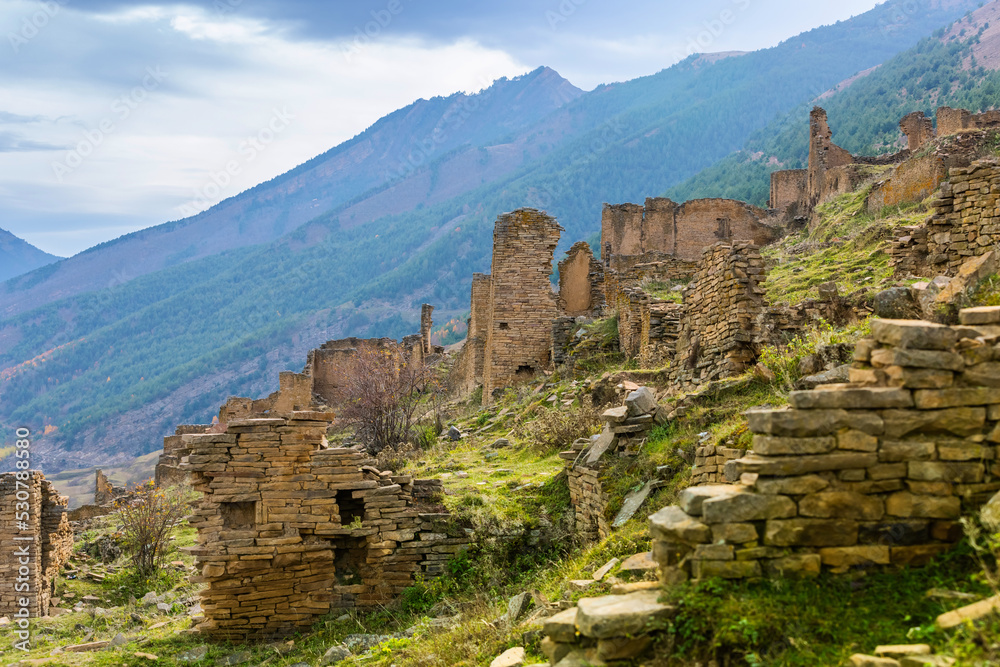 Ruins and towers of the abandoned village of Goor, Dagestan, Russia. Stone towers on the background of blue sky on the emerald hills. Panoramic view of the ancient Goor settlement among the mountains