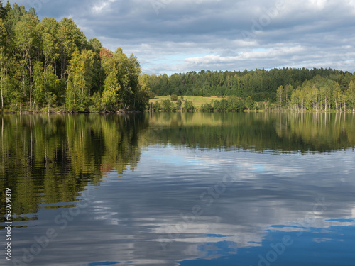 Typical autumn landscape in the Republic of Karelia, northwest Russia. Lake in calm weather, forest, clouds on the sky