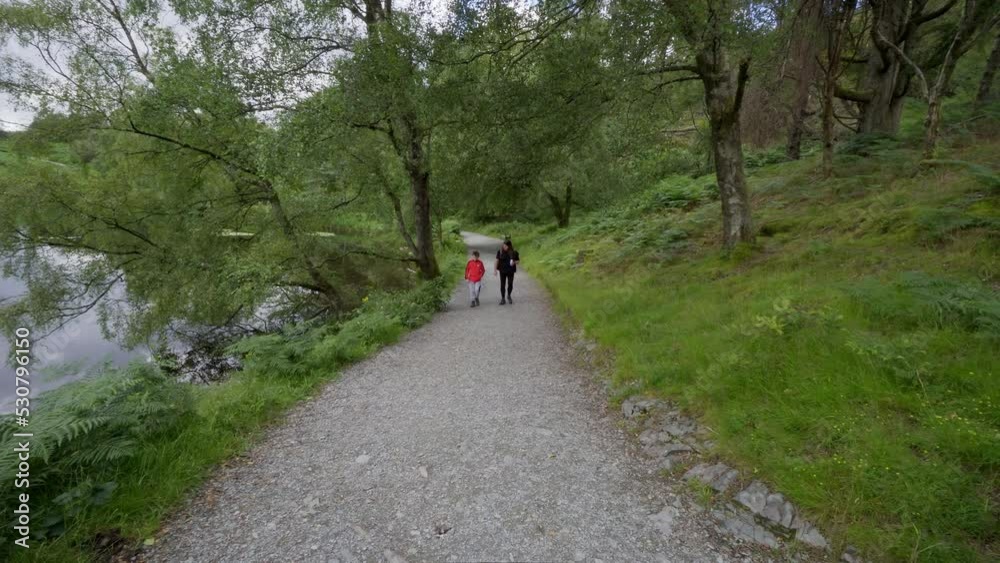Women and young boy walking, hiking through countryside with backpacks traveling over rough ground. Walkers, Hikers in the Lake District National Park Women and young boy walking, hiking through countryside with backpacks traveling over rough ground. Walkers, Hikers in the Lake District National Park