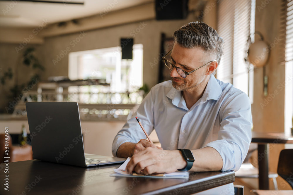 European grey man working with papers and laptop at office