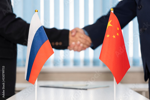 Political flags of russia and chinese on table in international negotiation room. concept of negotiations, collaboration and cooperation of countries. agreement between governments. photo